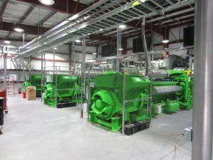 Interior photograph of a power plant with turbines painted bright green.
