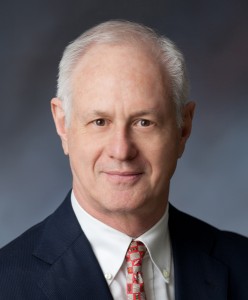 Headshot of a white haired gentleman wearing a suit and tie.